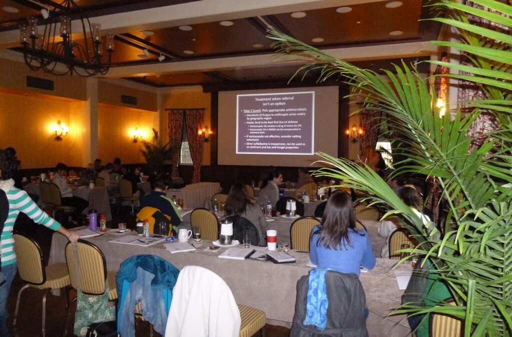 a group of people sitting at a table in a room with a projector screen